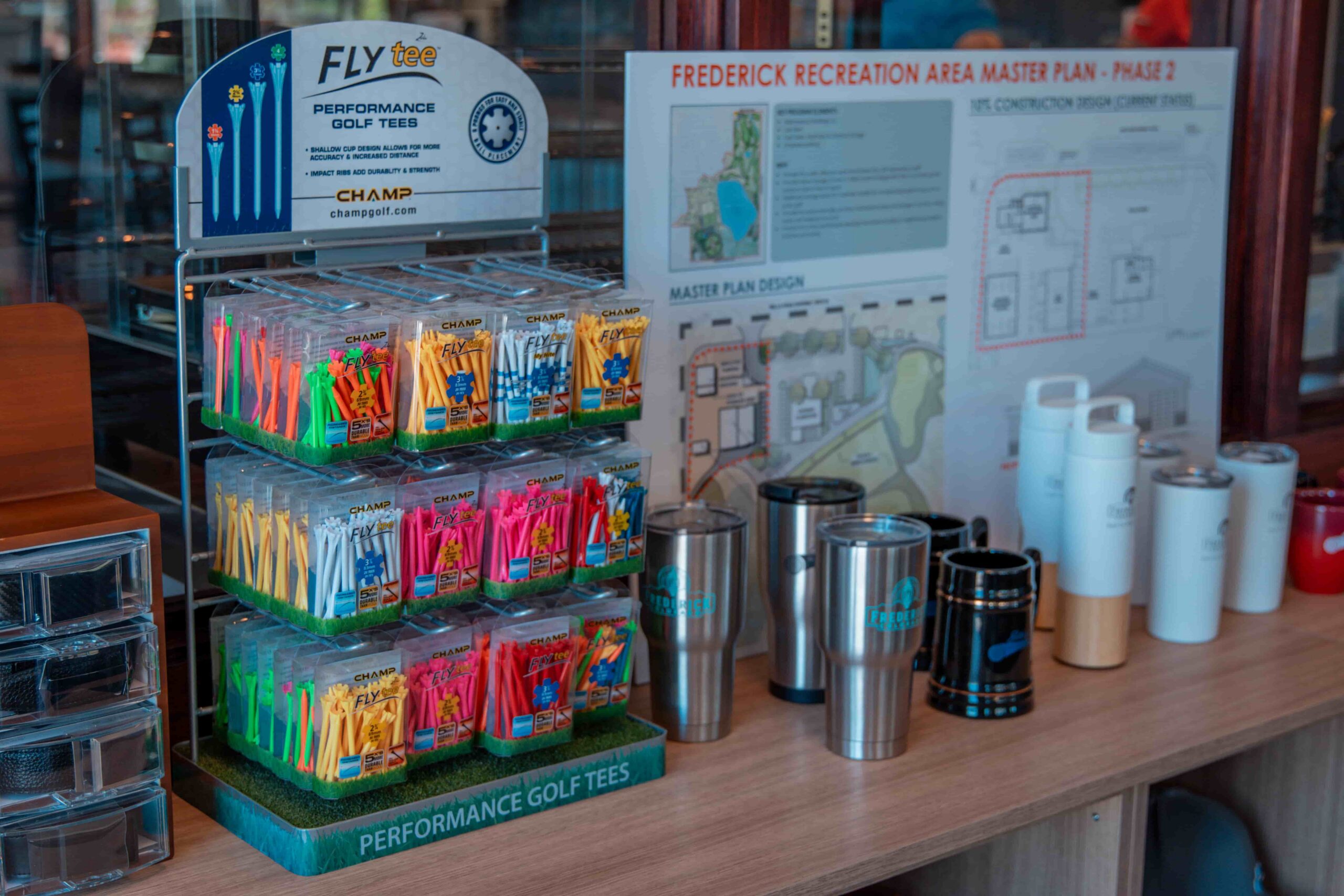 Display of colorful golf tees and various drink containers in a golf shop setting.